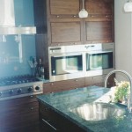 The wood in this kitchen is walnut, the back splash is glass, and the granite tops have green transparent flakes in them which compliment the glass. The side by side ovens are flush with the cabinet doors and have the same 3/32 in. reveal.